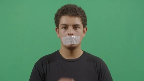 Young boy remove adhesive tape covering the mouth like it won't be quiet anymore Stock Footage 115338854