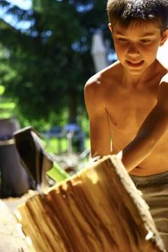 Young boy removing freshly split log from wedge during firewood preparation Stock-Fotos