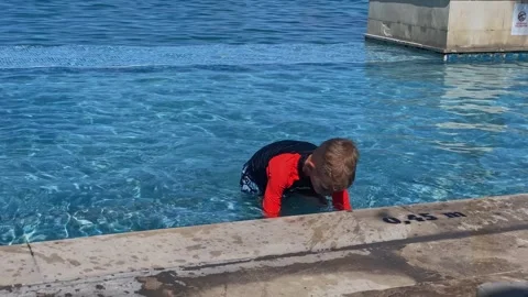 Young Boy Rests By Pool. Child Lounges Peacefully Beside Tiled Pool Vídeos de archivo 335591627