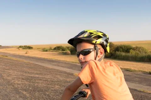 A young boy riding alone on a bicycle on the dam at the North Sea between hig Stock Photos