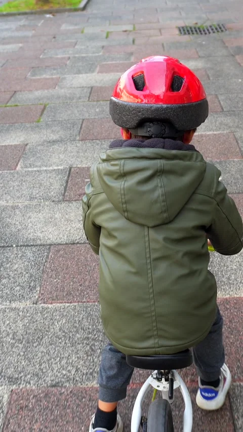 A young boy is riding a bicycle down a sidewalk Stock Footage 292454107