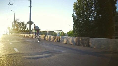 Young boy riding a bicycle on the empty sunny road sunrise slow motion rapid Stock Footage 78039687