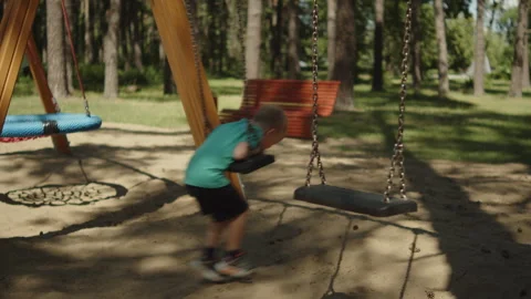 Young boy riding a chain swing at an outdoor park playground. Stock-Footage 343207989