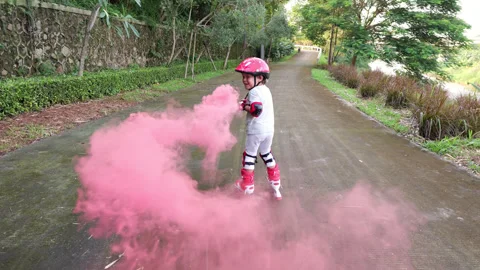 Young boy roller skating slowly and playing with pink smoke bomb Stock Footage 303625044