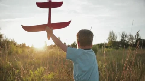 A young boy running across a field in with a pink toy airplane in his hand 스톡 동영상 117589367