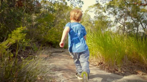 Young boy running and exploring along a bush track slow motion Stock Footage 130225549