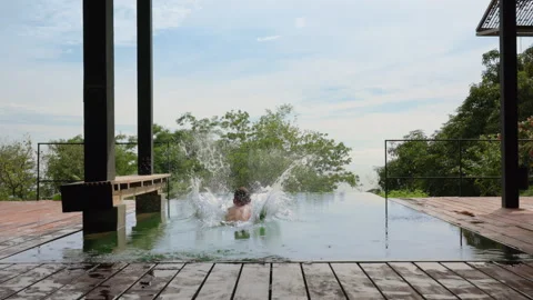 Young Boy Running and Jumping Into Infinity Pool in Slow Motion at Resort. Stock Footage 338368193