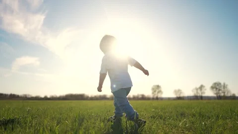 Young boy running through field. Silhouette of baby running in the grass on a Stock Footage 320472188