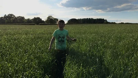 Young boy running through fresh summer grass in the British countryside 스톡 동영상 112102931