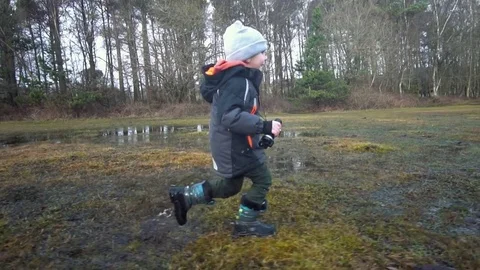 Young Boy Running Through Puddle in the forest  with binoculars in hand Stock Footage 84315300