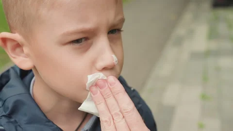 Young boy with runny nose. Boy uncomfortable as parent cleans his nose carefully Stock Footage 333099741