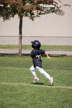 Young boy runs to first base during baseball game Stock Photos