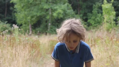 A  young boy runs through a field then takes a breath and walks on Stock Footage 208110467