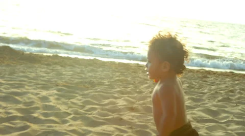 A young boy runs through the sand at the beach and then falls down 스톡 동영상 33894277