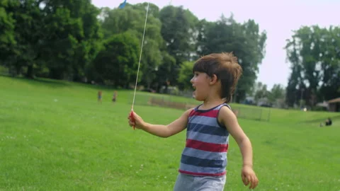 A young boy runs towards the camera with a kite in a park Video stock 143622149