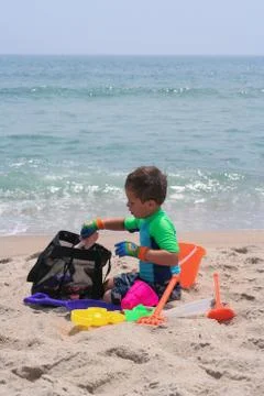 Young boy on the sandy beach playing with bucket ands shovel 库存照片