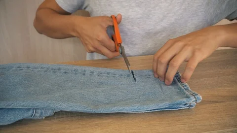 Young Boy with scissors cutting fabric jeans denim making  Stock Footage 96194972