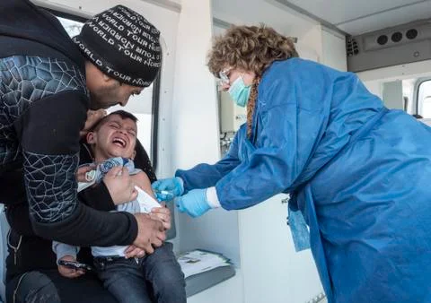 A young boy screaming in pain while taking an injection from a doctor Stock Photos