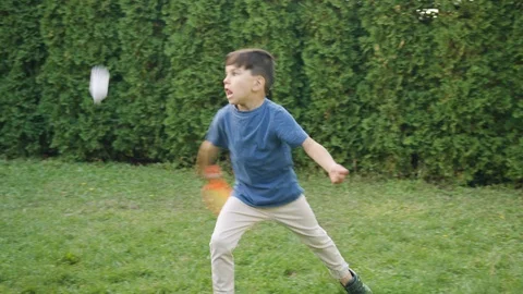 Young boy serving while playing badminton on grass in backyard Stock-Footage 119991448