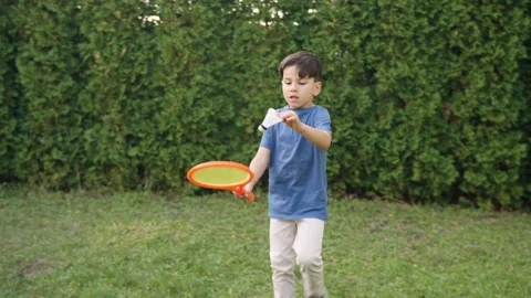 Young boy serving while playing badminton on grass in backyard 스톡 동영상 119991519