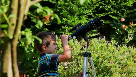 Young Boy Sets Up a Telescope in His Garden to Watch the Sky Stock Footage 314890315