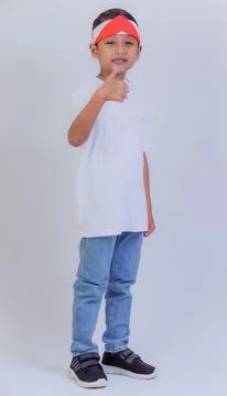 A young boy shows a thumbs-up while wearing a red and white headband, white.. Foto stock