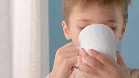 Young boy sipping warm beverage from white ceramic mug Video stock 330065009