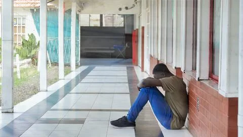 Young boy sitting alone with sad feeling at school. African child in depres.. Stock Photos