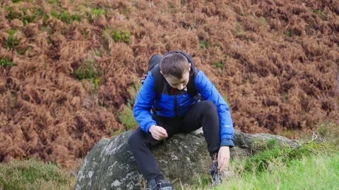 Young boy sitting and resting, fastening his walking boots, in a autumn out.. Stockbeeldmateriaal 254803278