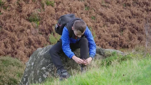 Young boy sitting and resting, fastening his walking boots, in a autumn out.. Vidéo 254803458