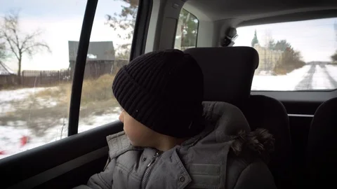 Young Boy Sitting on the back seat in a car listening to music and looking Video stock 98694149