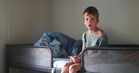 Young boy sitting on bed talking and explaining Video stock 292888443