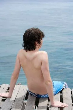 Young boy sitting on dock Stock Photos