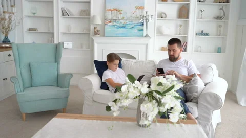 Young boy sitting with father at the sofa and using pc tablet. gadget addiction Stock Footage 115091124