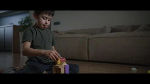 A young boy is sitting on the floor having fun playing with wooden blocks Stock Footage 276905964