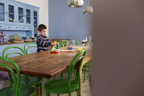 Young Boy Sitting At Kitchen Table And Painting Picture Stock Photos
