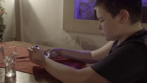 Young boy sitting in the restaurant and typing on smartphone. Video stock 84088749