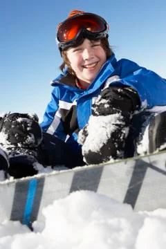 Young Boy Sitting In Snow With Snowboard Stock Photos