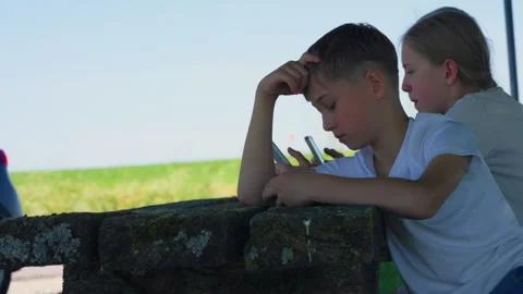 Young Boy Sitting on Stone Table and Looking at Smartphone Stock Footage 339031715
