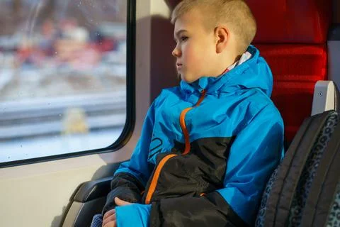 Young Boy Sitting by Train Window Looking Outside During Winter Journey Foto stock