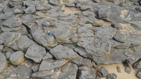 A young boy skillfully jumps from one large rock to another on a rugged rocky Video stock 291074252