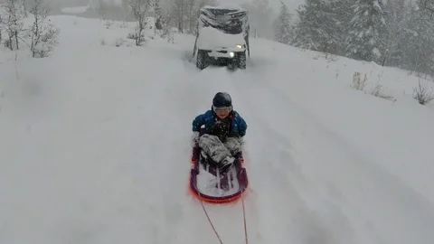 Young boy sledding behind an ATV in a snow storm 스톡 동영상 124296491