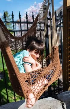 Young boy sleeping in a hammock in a backyard on a sunny day. Stock Photos