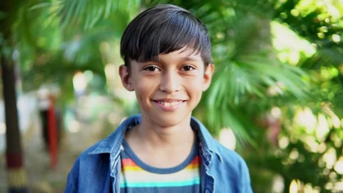 Young boy smiles at camera in a tropical garden setting Stock Footage 312690435