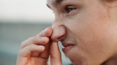 Young boy sniffs unpleasant odor. Child presses nose in outdoor setting Stock Footage 332365508