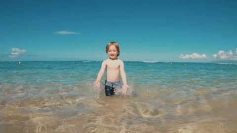 Young boy splashes in ocean water at beach. 스톡 동영상 131349706