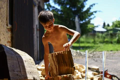 Young boy stacking and organizing split firewood after working outdoors Stock Photos