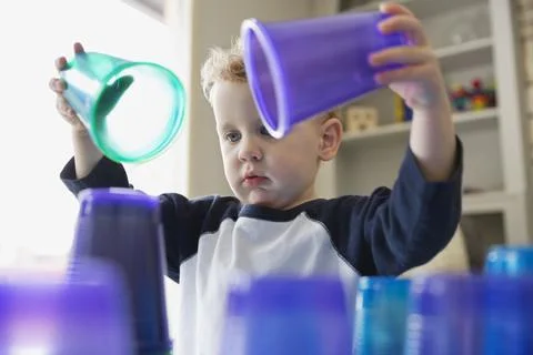 Young boy stacking plastic cups at home Stock Photos