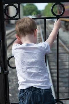 Young boy standing at back of train looking down at track Stock Photos