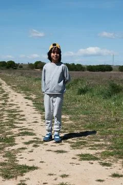 Young boy standing on dirt path in field Stock Photos